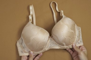 İşlenmiş desenli bej dantelli sutyen Elleri Kahverengi Arkaplanda, Yumuşak ve Zarif