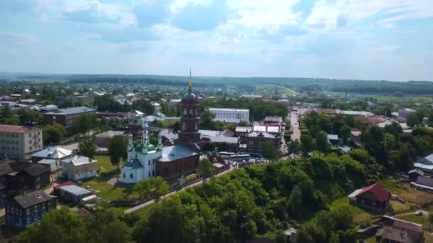 緑の木と多くの通りや建物を持つ夏の都市の空中ビュー クリップ 赤レンガ教会の周りを飛んでいる — ストック動画