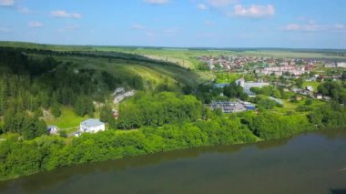 Nehir kıyısındaki bir köyün hava görüntüsü. Şarjör. Yazın üzerinde uçan yeşil doğa ve binalar