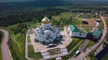  Ormanı ve dağları olan bir yaz manzarası. Şarjör. Süslü yeşil bir orman ve ortasında bir köyle çevrili güzel bir köylü tapınağı. Yüksek kalite 4k görüntü