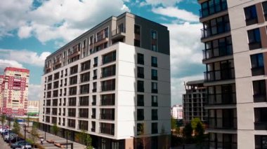 Bulutlu mavi bir arka planda, çok katlı bir binanın etrafında uçuyor. Stok görüntüleri. Yeni yapılmış bir apartman.