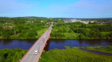 Geniş bir nehri geçen uzun bir köprünün havadan görüntüsü. Şarjör. Resimli kırsal alan boyunca giden arabalar