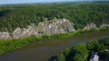 Uçsuz bucaksız orman ve kaya kayalıkları ile vahşi doğanın havadan görünüşü. Şarjör. Yaz ağaçları boyunca güzel bir nehir.