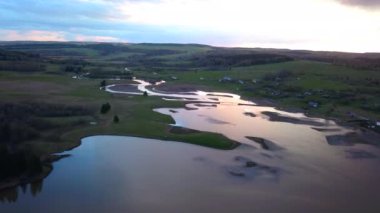 Günbatımı arkaplanındaki bataklık bir arazinin havadan görünüşü. Şarjör. Nehir ve tarlaları büküyor