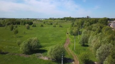 Güneşli bir yaz gününde kır yolunda araba gezintisi. Şarjör. Araba yazın yeşil arazide yol boyunca hareket ediyor. Güneşli bir günde yeşil çimenli arabalı arazi yolu. 