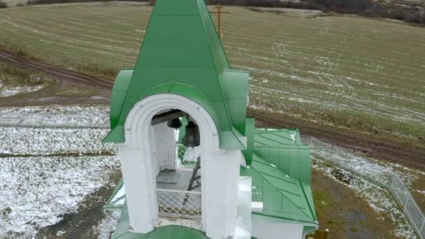 黄金の十字架と鐘を持つ白と緑の教会の空想的な眺め クリップ 雪で覆われた緑地 — ストック動画