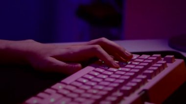 Bilgisayar klavyesinin tuşlarına basan bir adamın parmaklarını kapat. Stok görüntüleri. Pembe ışıklandırmalı karanlık oda