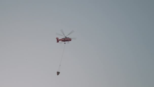 貨物が付いている飛行ヘリコプター アクション 貨物を落とす大きな赤い飛行ヘリコプターが付いている霧の灰色の空 高品質の4K映像 — ストック動画