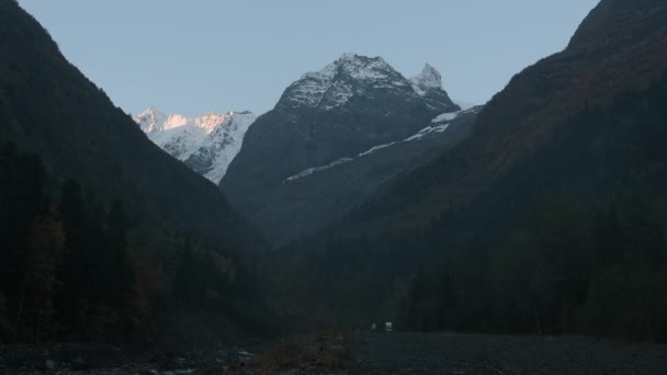 深谷在山脚下 深山密布的山谷中的路 有很高的悬崖 秋天雪峰背景下的岩石群山中的黑暗山谷 — 图库视频影像