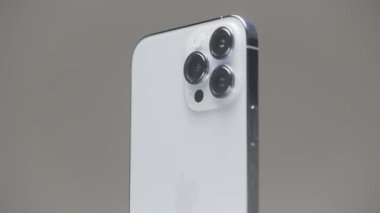 Almanya - Berlin, 27 Eylül 2022: Yeni iPhone 13, gri duvar arka planında yavaşça izole edildi. Başla. Metal çantalı ve üç kameralı yeni iPhone 'un şık dış tasarımı