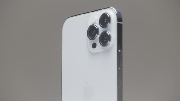 ドイツ ベルリン 2022年9月27日 新しいIphone 13はゆっくりと灰色の壁の背景で孤立しました アクション 金属ケースと3つのカメラを備えた新しいIphoneのスタイリッシュな外観デザイン — ストック動画