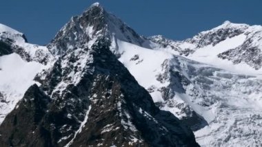 Destansı kış karının havadan görünüşü mavi arka plandaki dağları kapladı. Yaratıcı. Keskin yamaçlar ve kayalıklar