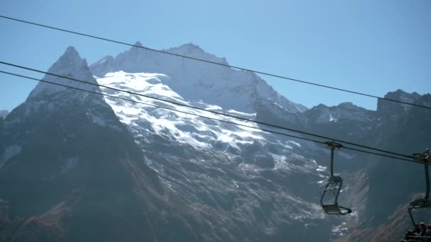 在高山和阳光灿烂的天空背景上移动的电梯 秋天的青草在雪峰群山中飘扬 美丽的风景和滑雪电梯爬上了多山的山峰 — 图库视频影像