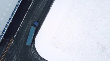 Kocaman mavi bir kamyonu taşıyordu. Kuş bakışı görüş. Yaratıcı. Büyük bir arabanın malları taşıdığı kış manzarası. Yüksek kalite 4k görüntü