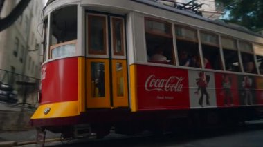 Portekiz, Lizbon - 17 Temmuz 2022: Avrupa 'nın dar sokaklarından geçen tramvaylar. Başla. Tramvaylar eski şehrin Avrupa sokaklarında dolaşıyorlar. Reklamlı tramvaylar dar geçitlerden geçer