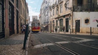 Portekiz, Lizbon - 17 Temmuz 2022: Avrupa 'nın dar sokaklarından geçen tramvaylar. Başla. Tramvaylar eski şehrin Avrupa sokaklarında dolaşıyorlar. Reklamlı tramvaylar dar geçitlerden geçer