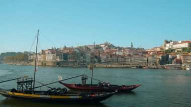 Portekiz, Porto - 14 Temmuz 2022 Portekiz bayrağı taşıyan eski ahşap tekneler. Başla. Portekiz 'in ulusal ahşap tekneleri. Güneşli yaz gününde güney şehrinin arka planında tekneleri olan güzel bir liman.. 