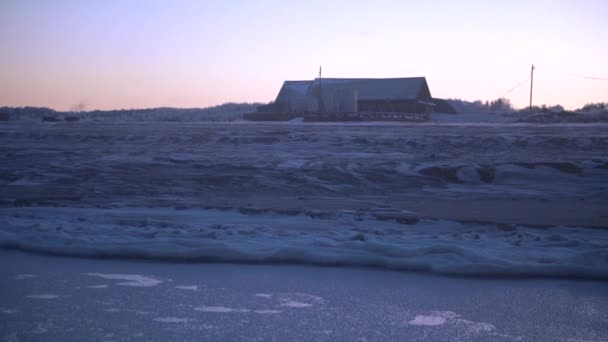 朝の地平線に家がある凍った野原の風景 クリップ 雪原の冷たい暗い風景と地平線上の古い納屋 朝のウィンタースノーフィールド — ストック動画