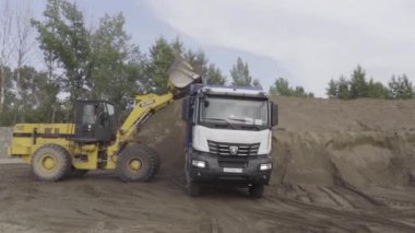 Berlin - Almanya, 6 Aralık 2022: İnşaat kazıcı kamyonu kumla dolduruyor. Sahne. Zemin kazmak için ağır ekipman.