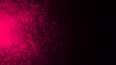 Turuncu ve pembe parıltılı siyah arka plan. Hareket. Çizgi film animasyonunda parlak, küçük, yanardöner parçacıklar farklı yönlere sıçrar. Yüksek kalite 4k görüntü