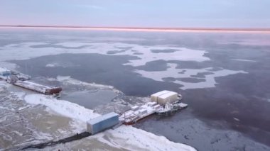 Deniz boşaltılan kışın kıyısı. Şarjör. Karlı sahil ve kargo gemileriyle kış manzarası. Kış günü mavnaların boşaltılacağı yer.