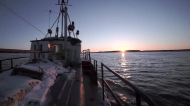 Deniz manzaralı bir balıkçı teknesinde. Şarjör. Ufuk manzaralı bir balıkçı teknesinde yürüyorum. Balıkçı teknesi ufuktaki güneşin arka planına yelken açıyor. 