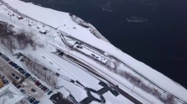 Şehir manzarasına kuşbakışı bir bakış. Şarjör. Küçük bir kasabada yolları ve arabaları olan kış nehri. Yüksek kalite 4k görüntü
