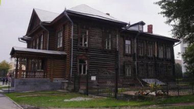 Eski ahşap bir ev. Stok görüntüleri. Vatandaşların yürüdüğü parkın arka planında ışıksız duran ahşaptan yapılmış iki katlı büyük bir ev. Yüksek kalite 4k görüntü