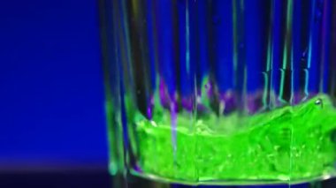 Yumuşak içecek, mavi arka planda izole edilmiş yeşil soda. Borsa klipsi. Suyun içinde kabarcıklar