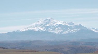 Karlı dağ arka planında sis ve bulutlar. Yaratıcı. Dağların eteğindeki sarı vadi