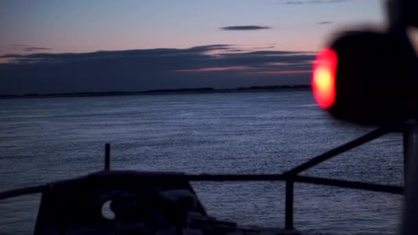 傍晚时分 在有海景的船上闪烁着朦胧的红光 黄昏时 从船上看到漆黑的大海和岸上 黄昏时在渔船上航行 — 图库视频影像