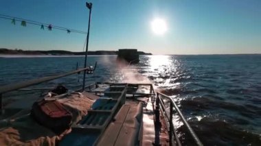 Güneşli bir günde tekneden yüzen mavnanın görüntüsü. Şarjör. Parlak güneşin arka planında mavnayı çeken bir tekne. Güneşli bir günde mavnayla deniz ulaşımı. 