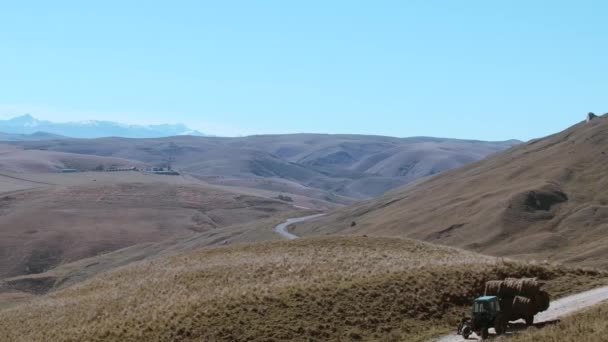 空旷的田野和从直升机上夺走的高山 巨大的丘陵伸展在道路上 拖拉机在蓝天的映衬下行驶 高质量的4K镜头 — 图库视频影像