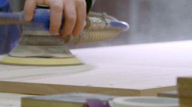 Odada tamirat var. Yaratıcı. Güçlü elleri olan bir adam mobilya montajı için özel yüzeyleri öğütür ve temizler. Yüksek kalite 4k görüntü