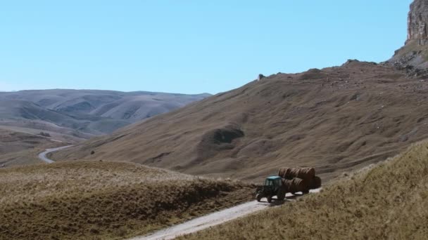 空旷的田野和从直升机上夺走的高山 巨大的丘陵伸展在道路上 拖拉机在蓝天的映衬下行驶 高质量的4K镜头 — 图库视频影像