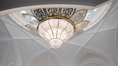 Tavanda taç yaprakları ve oyulmuş süs eşyasıyla zarif bir avize. Sahne. Bir salonun iç detayları.