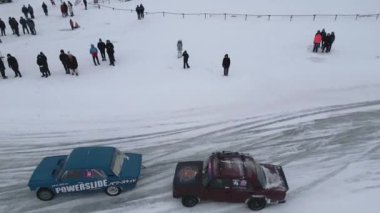 Kış eğlencesi helikopterden çekildi. Şarjör. Yarışmalara giden arabalarda kış sürükleniyor ve insanlar etrafı seyrediyor. Yüksek kalite 4k görüntü