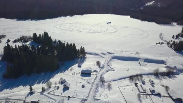 ヘリコプターから撮影された冬の景色 クリップ 日光が降る森の真ん中にある小さな村 高品質の4K映像 — ストック動画