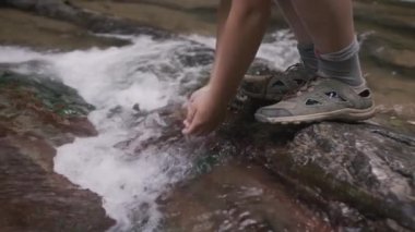 Yavaş çekimde dere kenarından su içen çocuğa yaklaş. Yaratıcı. Oğlan ve dağlık soğuk dere