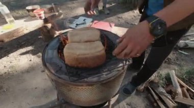 İnşaat alanında iki parçaya kesilmiş somun ekmek koyan bir adam. Şarjör. Dışarıda öğle yemeği hazırlıyorum.