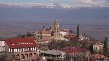 Dağların arka planında taş kulesi olan antik şehir manzarası. Başla. Tepedeki antik şehir, dağ sırasının arkasında karla kaplı. Ufukta dağları olan antik şehir. 