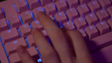 Oyun sırasında parmaklarınızı klavyeye bastırın. Stok görüntüleri. Bilgisayar oyunları için parlak pembe klavye. Parmaklar bilgisayar klavyesinin oyun tuşlarına basar. 