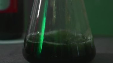 Kimyasal sıvının yakın çekimi mataraya dökülüyor. Stok görüntüleri. Sıvı dolum şişesi akışı. Laboratuvar deneyi için kimyasallar şeffaf şişeye dökülür..