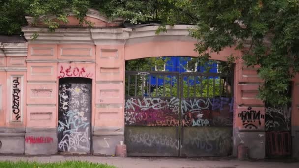城市里有涂鸦的旧建筑的正面 库存录像 旧建筑正面和栅栏上的涂鸦 夏天的时候在城里画了些涂鸦的旧建筑 — 图库视频影像