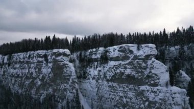 Buz kaplı uçurumlu, kar manzaralı bir hava. Şarjör. Ormanlı tepeli beyaz uçurum kenarı