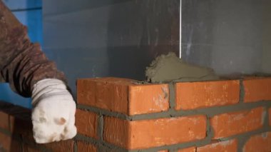 İnşaat süreci. Şarjör. Eldivenli bir adam, çimento takviyeli bir tuğlaya çabucak tuğla koyar. Yüksek kalite 4k görüntü
