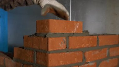 İnşaat süreci. Şarjör. Eldivenli bir adam, çimento takviyeli bir tuğlaya çabucak tuğla koyar. Yüksek kalite 4k görüntü