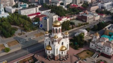 Bir sürü konut ve altın kubbeli bir kilisenin bulunduğu şehrin havadan görünüşü. Stok görüntüleri. Yaz şehri ve yeşil sokaklar