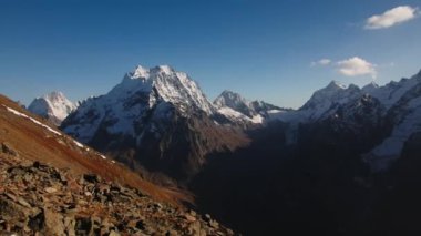 Güneşli bir günde karlı zirveleri olan bir dağ manzarası. Yaratıcı. Güneşli yaz gününde tepeleri karlı çöl dağları. Kayalık tepeleri olan güzel bir dağ manzarası..