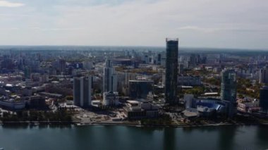 Nehirli şehir panoramasındaki modern yüksek binaların en üst görüntüsü. Stok görüntüleri. Güneşli bir günde şehrin güzel kuş bakışı manzarası. Güneşli yaz aylarında gökdelenleri ve nehri olan modern şehrin manzarası.